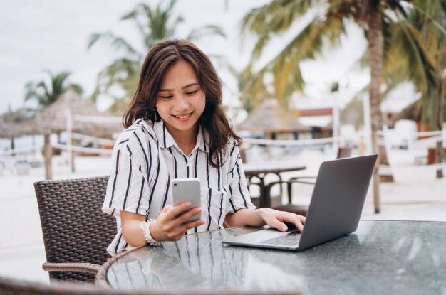 Asian woman working on laptop on a vacation Free Photo