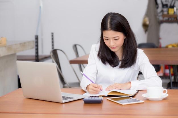 Business asian woman writing on notebook on table with laptop ...